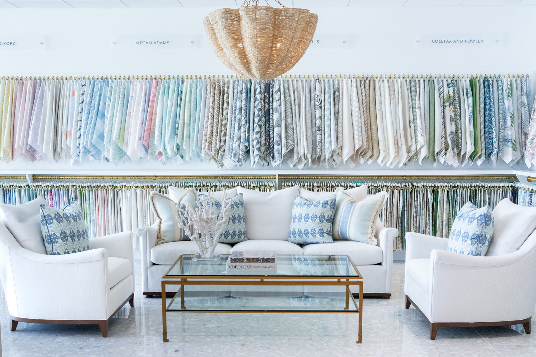 image of hive trade showroom fabric wall with white and blue seating area in front with blue and white pillows