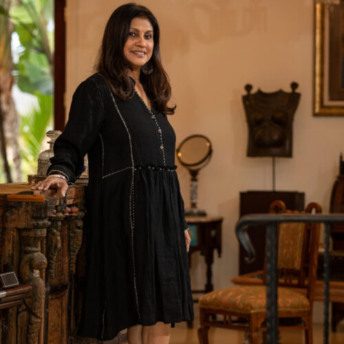 Viji Alamwar wearing a black dress standing next to a console table