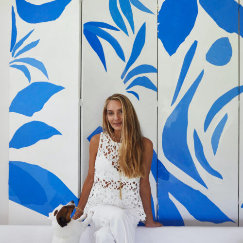 Lulu DK and her dog sitting in front if a white and blue artwork